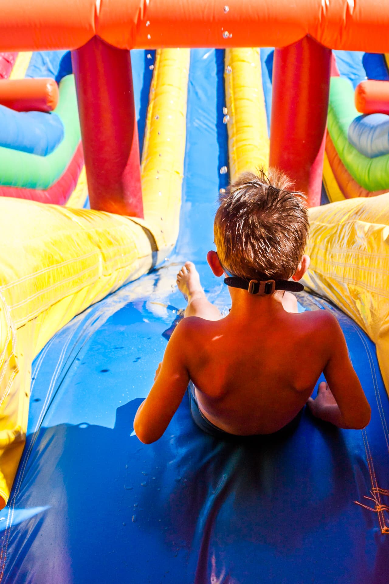 Child sliding through a colorful inflatable water slide — party rental delivered in Clewiston, FL