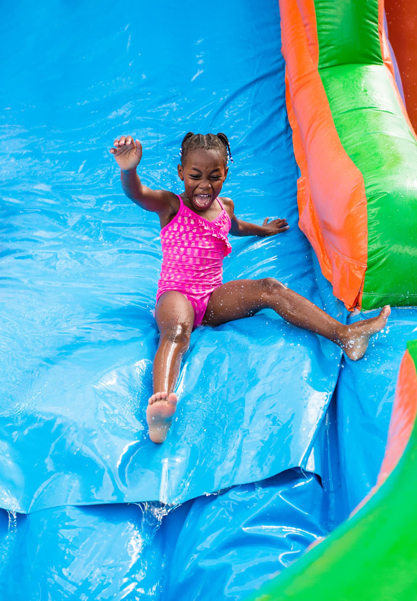 Child sliding down a colorful water slide — party rental delivered in Cape Coral, FL